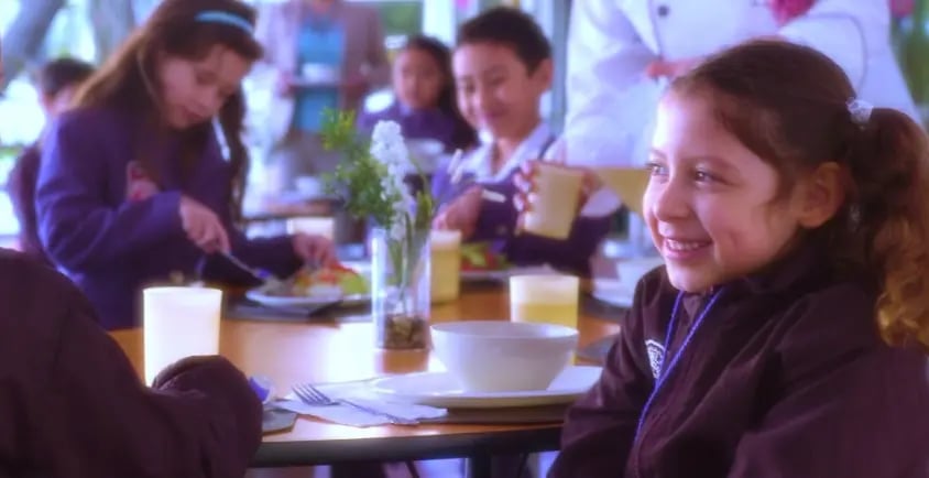 Instalaciones del comedor escolar limpias, iluminadas y organizadas para el horario de alimentos.
